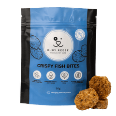 A blue pouch of RUBY REESE CRISPY FISH BITES natural dog treats with a ziplock and a CRISPY FISH BITE lying in front of it