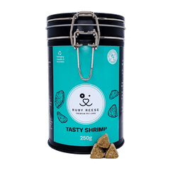 A black tin of RUBY REESE TASTY SHRIMP natural dog treats with an turquoise label with some treats spilled in front of it